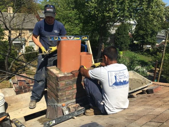 Men installing brick on a chimney 