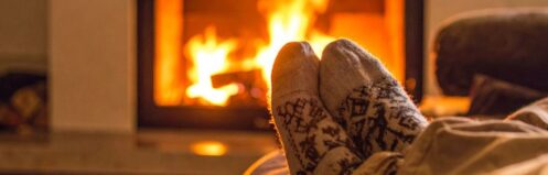 cozy socks are visible of someone sitting in front of a fireplace being used as a supplemental heat source in their home in Richmond, VA
